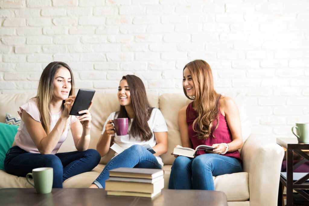 Three girl sitting with coffee and books on a couch